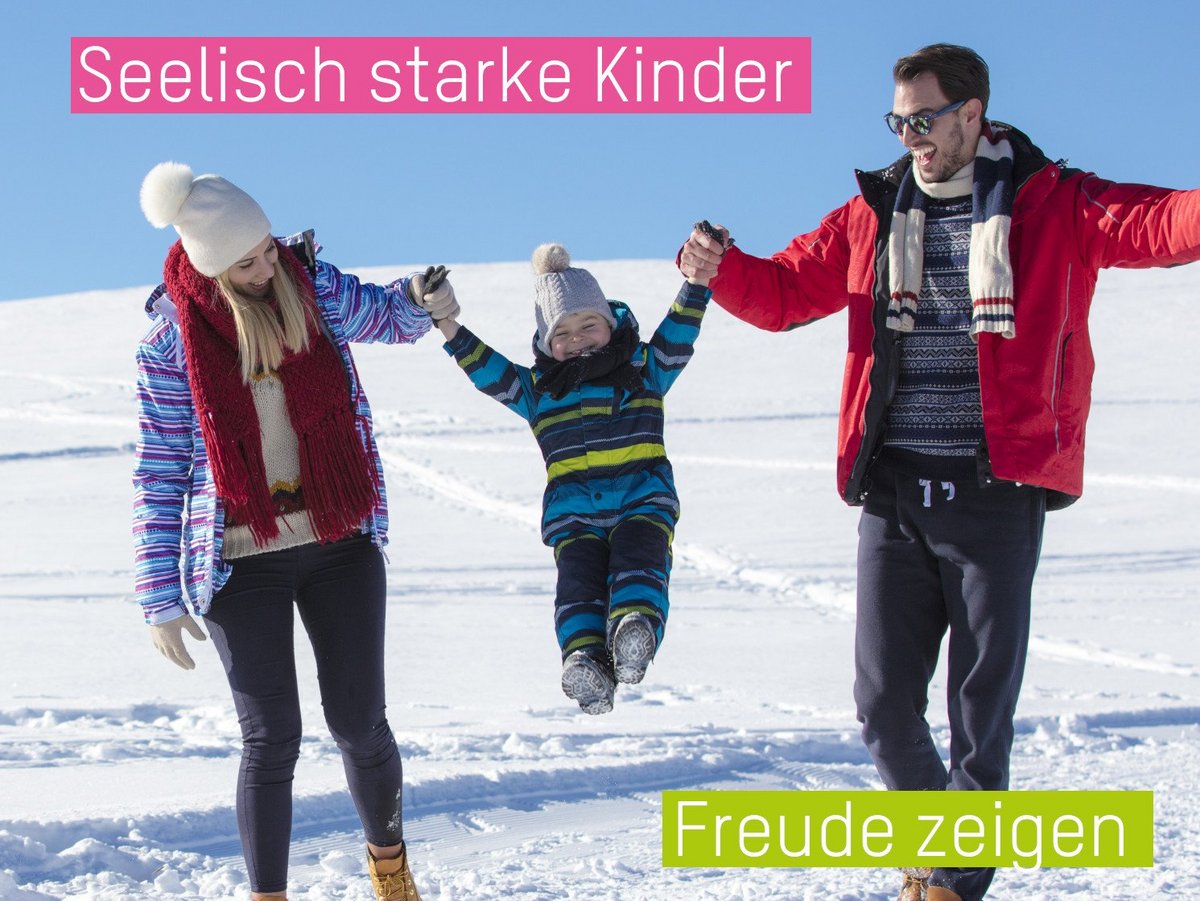 Elternpaar im Schnee, dass sein Kind zwischen sich an den Armen hochhebt.