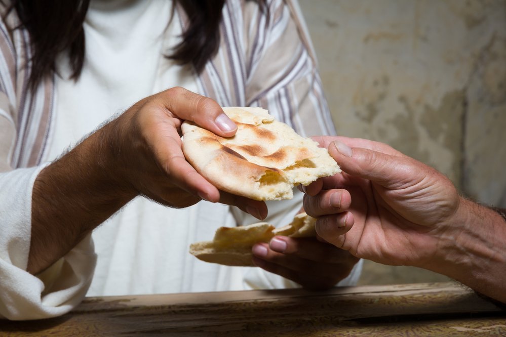 Hand reicht einer anderen Hand Brot