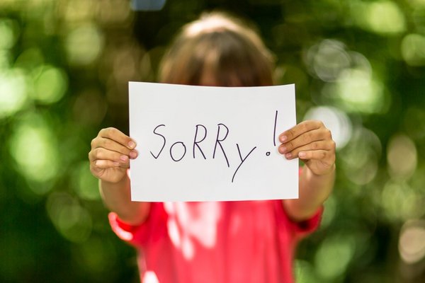 Unscharfes Kind mit Zettel "Sorry"
