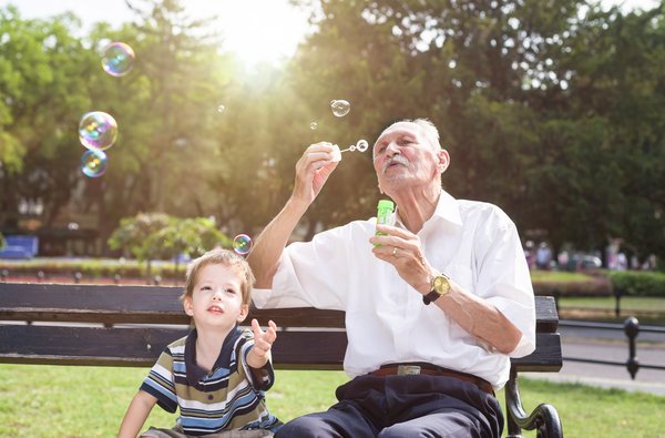 ältere Mann mit Kind bläst Seifenblasen in die Luft